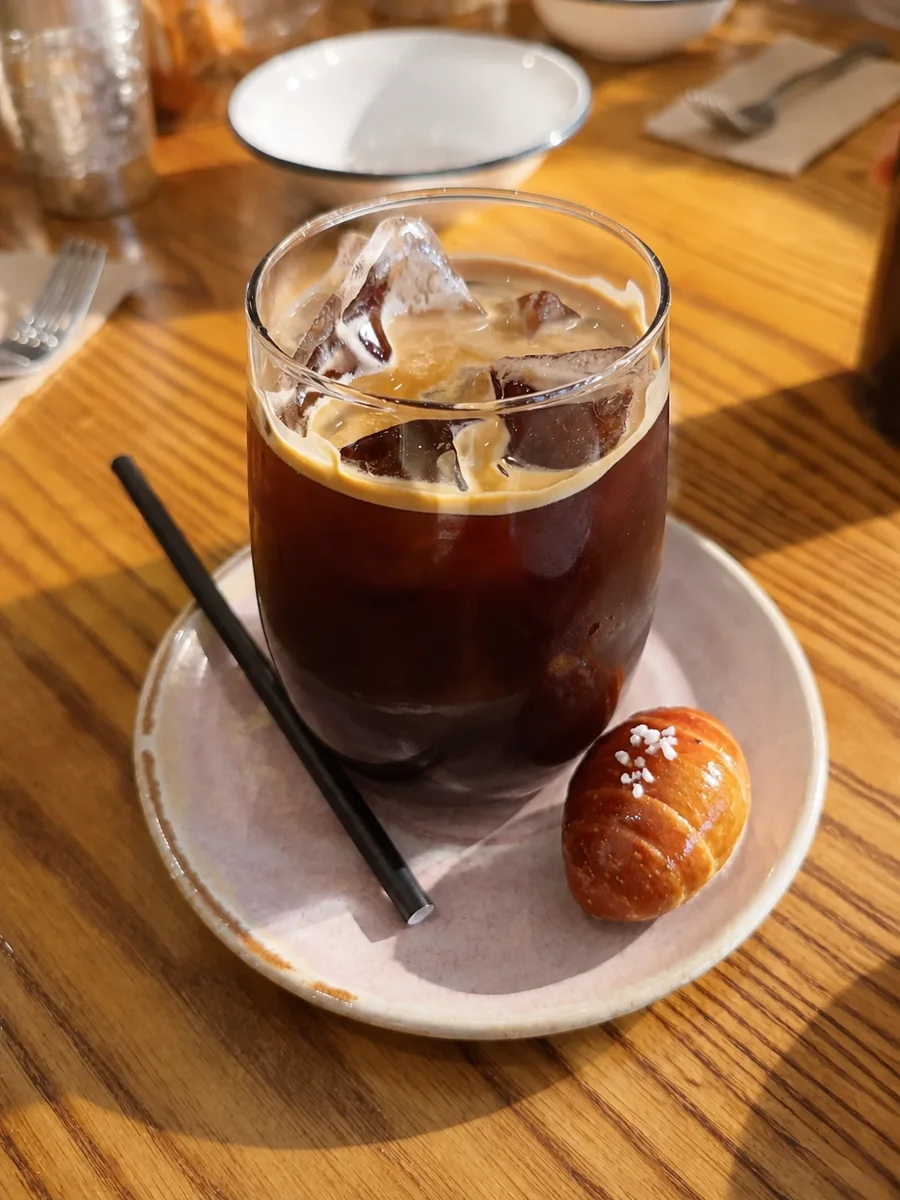 Iced black coffee and a small pastry on the café table
